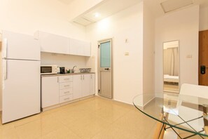 A compact kitchen with white cabinets, a microwave, and a glass table. - Port city haifa - studio 214 (Haifa)