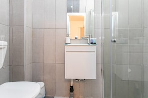 A modern bathroom with a glass shower enclosure, a white sink, and a toilet. - Port city haifa - studio 214 (Haifa)