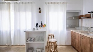 A modern kitchen with white cabinetry, a wooden stool, and a breakfast bar. - Port city haifa - Studio 215 (Haifa)