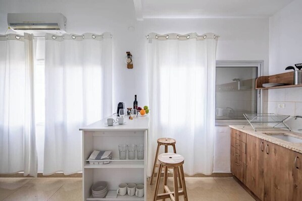 Eine moderne Küche mit weißen Schränken, einem Holzhocker und einer Frühstückstheke.