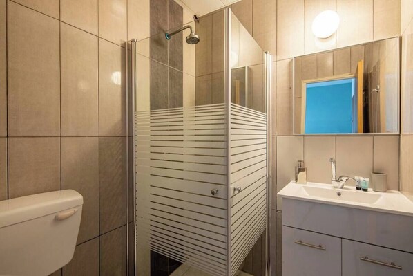 A modern bathroom with a glass shower enclosure, a toilet, and a sink with a mirror. - Port city haifa - Studio 215 (Haifa)