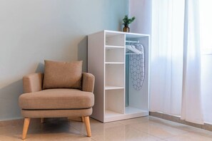 A room with a beige armchair, a white wardrobe with a geometric design, and a potted plant on top. - Downtown Haifa Studio 215, Near Port, AC & WiFi (Haifa)