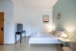 A bedroom with a bed, a bedside table, a television, and a lamp. - Downtown Haifa Studio 215, Near Port, AC & WiFi (Haifa)