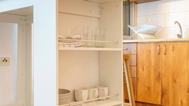 Una cucina con mobili bianchi, un piano di lavoro in legno e un lavello.