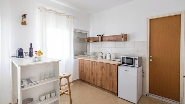 A compact kitchen with white cabinets, a microwave, a kettle, and a small refrigerator. - Port city haifa - Studio 215 (Haifa)