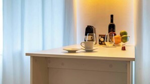 A small table with a coffee maker, a bottle, a cup, and a bowl of fruit. - Port city haifa - Studio 215 (Haifa)