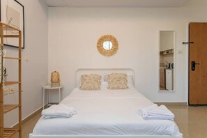 Ein Schlafzimmer mit einem Bett, zwei Kissen, einem Nachttisch, einem Spiegel, einer Holzleiter und einer Tür zu einem Badezimmer.