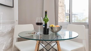 Ein Glastisch mit einer Weinflasche, einem Weinglas und einer Schale mit Obst.