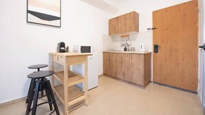 A compact kitchen with a wooden countertop, a coffee machine, a microwave, and a small stool. - Port city haifa - Studio 217 (Haifa)