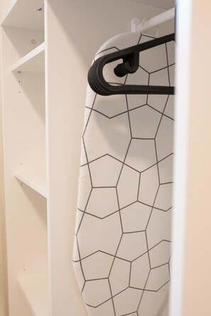 A white closet with a geometric-patterned garment hanging on a black hanger. - Port city haifa -  Studio 217 (Haifa)