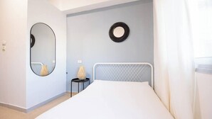 A bedroom with a bed, a round mirror, and a small table with a lamp. - Port city haifa - Studio 217 (Haifa)