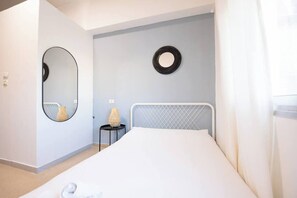 Ein Schlafzimmer mit einem Bett, einem runden Spiegel und einem kleinen Tisch mit einer Lampe.
