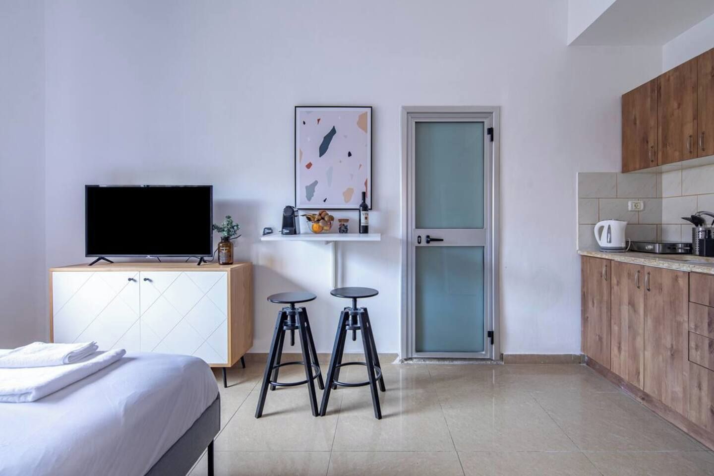 Une chambre d’hôtel avec un lit, une télévision, un coin cuisine et une porte.