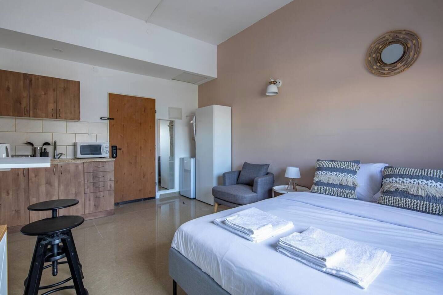 Une chambre d’hôtel moderne équipée d’un lit, d’un bureau, d’une chaise et d’une kitchenette.