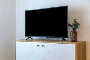 A television on a wooden cabinet with a plant beside it. - Port city haifa - Studio 218 (Haifa)