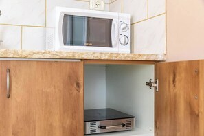 Eine Küche mit einer Mikrowelle auf der Arbeitsplatte, einem Holzschrank darunter und einer Schublade für Küchengeräte.