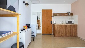 A compact kitchen with a microwave, kettle, and wooden cabinets. - Port city haifa - Studio 219 (Haifa)