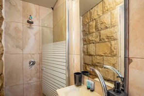 A bathroom with a shower, a sink, and a mirror. - Downtown Haifa Studio 219, Near Port, AC & WiFi (Haifa)