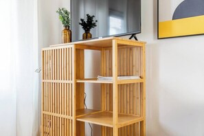 A wooden bookshelf with three shelves, a flat-screen TV mounted above it, and two decorative vases on the top shelf.