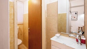 A bathroom with a wooden door, a white sink with a chrome faucet, and a mirror above the sink.