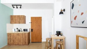 A compact kitchen with wooden cabinets, a microwave, and a wooden door.