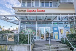 A liquor store with a glass facade, outdoor seating, and a Bud Light advertisement. - Central Van 3BR Upper Suite - Near Skytrain (Vancouver)