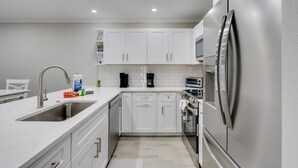 Een moderne keuken met witte kasten, roestvrijstalen apparatuur, een ingebouwde oven en een spoelbak.