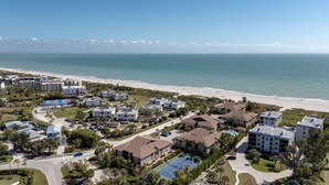 Een luchtbeeld van een kustbewoonde wijk met huizen aan het strand, een tennisbaan en een helder uitzicht op de oceaan.