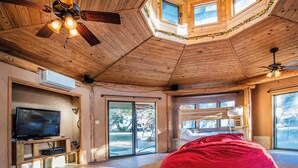 Ein geräumiger Raum mit großem Fernseher, Holzbalkendecke und einem roten Sitzsack.
