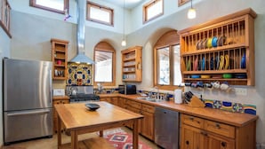 Eine Küche mit Holzschränken, einem Edelstahlkühlschrank, einem Holztisch und einer farbenfrohen Spritzschutzwand.