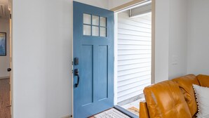 A blue door with a keypad lock, a brown leather couch, and a white wall.