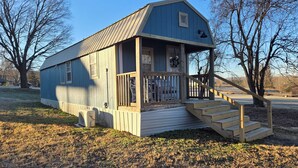 A small, single-story wooden building with a porch and a staircase leading to the entrance. - The Blue Goose, a charming house in Marshall, perfect for your getaway. (Marshall)