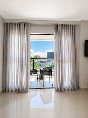 Une pièce dotée d’une grande porte-fenêtre coulissante qui donne sur un balcon extérieur avec deux chaises.