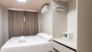 A hotel room with a bed, a wardrobe, a hanging clothes rack, and an air conditioning unit. - MIRAFLORES HOTEIS (Macapá)