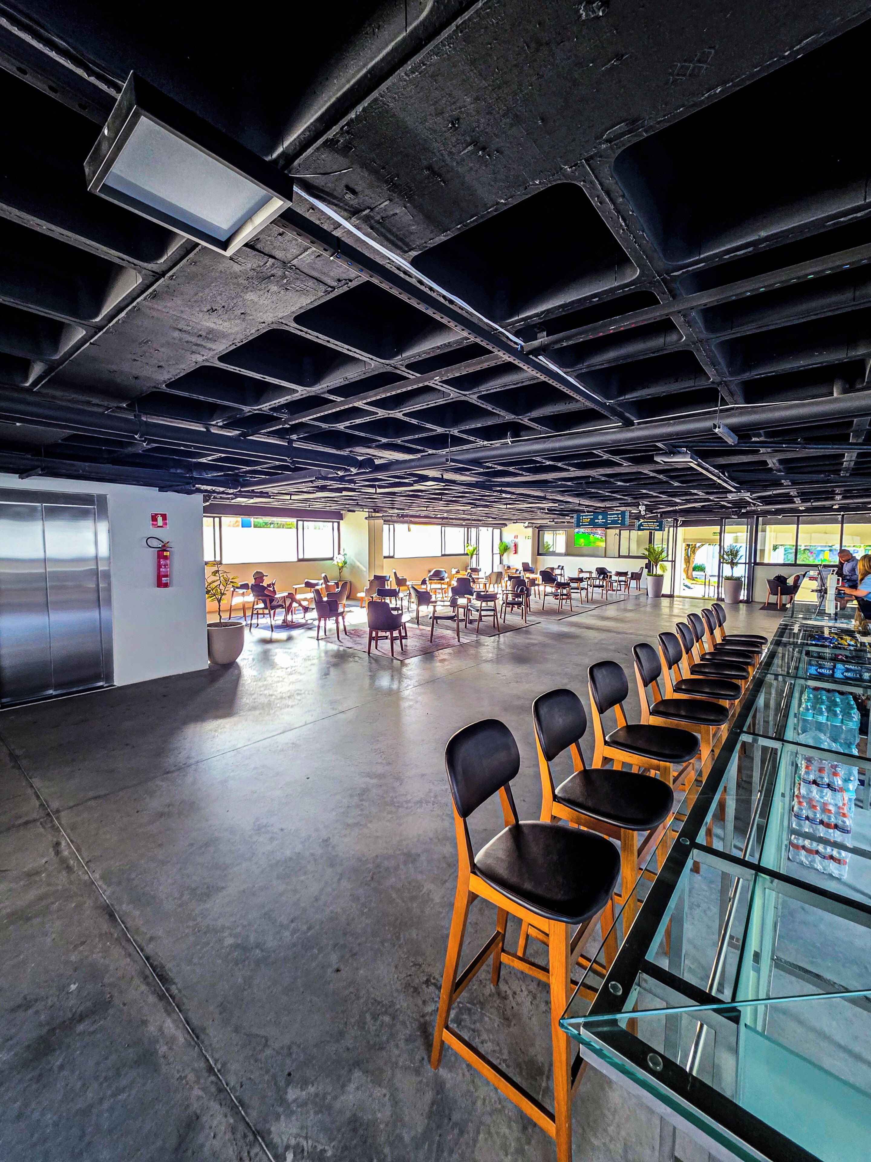 A spacious indoor area with rows of chairs, a glass display case, and a visible elevator.