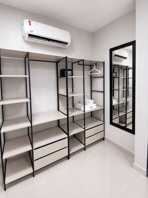 A modern closet with multiple shelves and hanging space, an air conditioning unit above, and a mirror on the wall. - MIRAFLORES HOTEIS (Macapá)