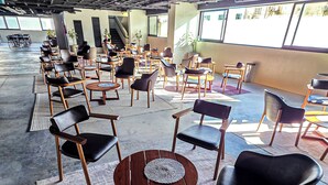 A spacious indoor area with multiple seating arrangements, including round tables and chairs, and a high ceiling with visible structural elements. - MIRAFLORES HOTEIS (Macapá)