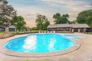 A swimming pool with lounge chairs, a stone wall, and a building with a roof in the background. - Pop’s Fishing Cabin - 
Lakeviews - Hot Tub - Kayaks - Nature & close to Branson (Branson)