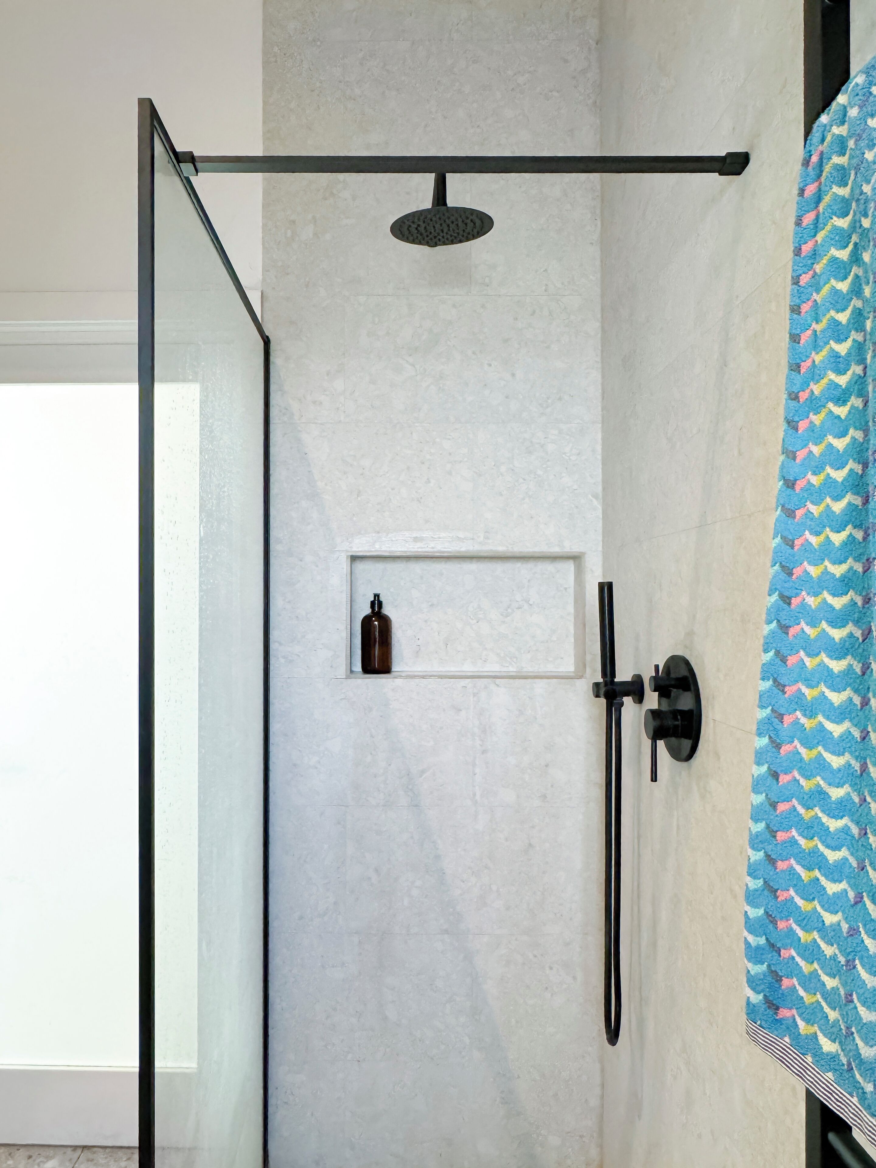 Ein modernes Duschbad mit Glasduschwand, Handbrause und Seifenspender.
