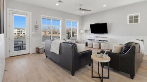 A modern living room with a sofa, a coffee table, and a TV. - GiGi's Jewel | Lakefront+ Pool+ Pet Friendly +Lift (Kingsland)