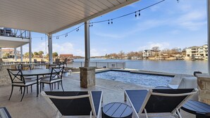 An outdoor patio with tables and chairs, a pool, and a view of a body of water and buildings. - GiGi's Jewel | Lakefront+ Pool+ Pet Friendly +Lift (Kingsland)
