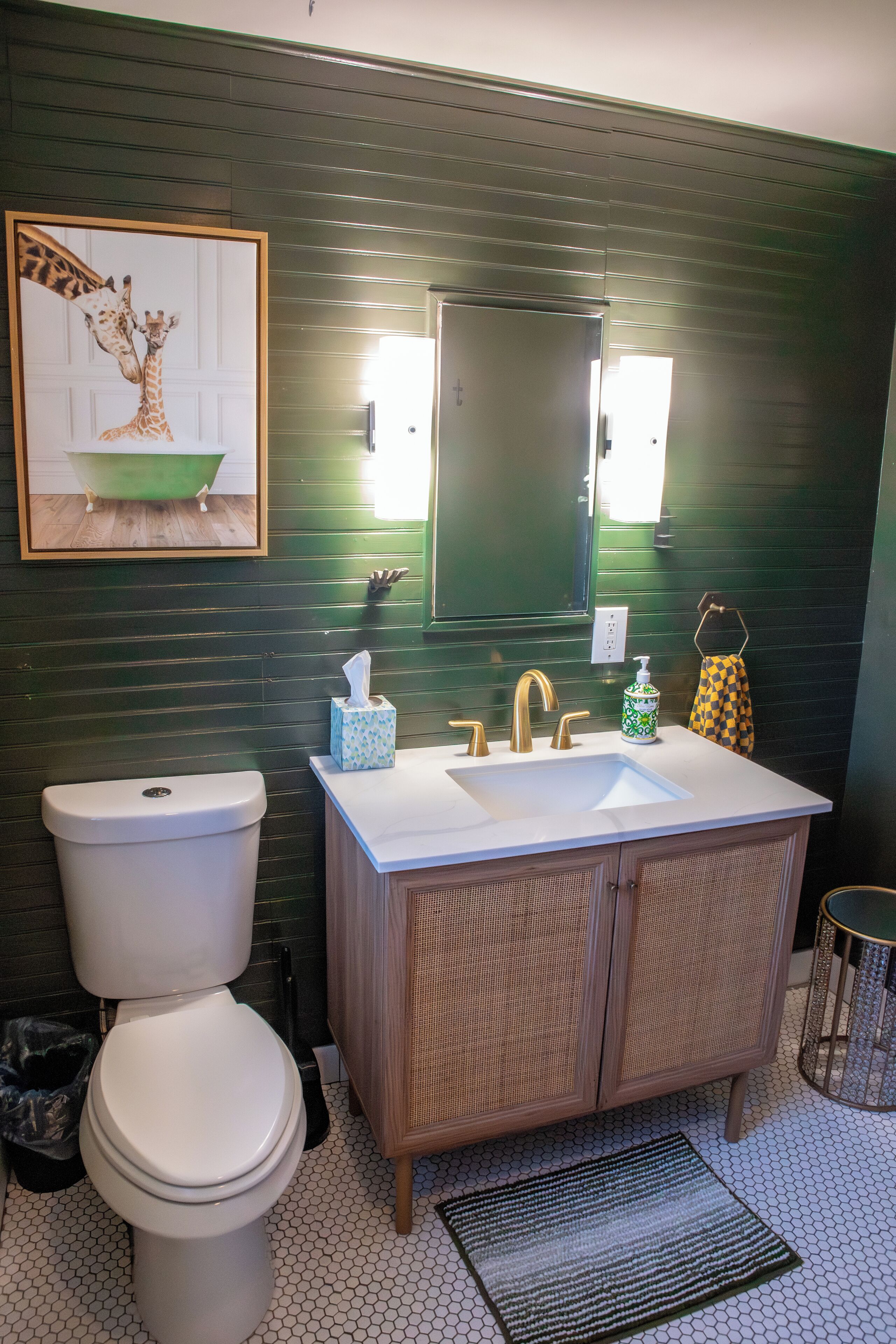 Een badkamer met een wit toilet, een wastafel met twee wasbakken, een spiegel en een ingelijst schilderij aan de muur.