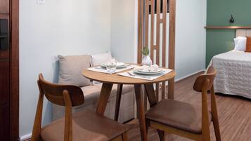 A room with a round wooden table, two chairs, a small white vase, and a hanging light fixture.