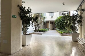 Un pati interior espaiós amb paviment de rajoles, plantes en testos i una banca blanca.