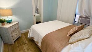 Ett sovrum med en säng, ett sängbord, en lampa och en spegel.