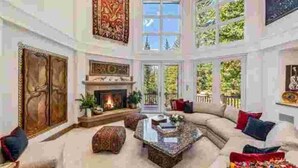 A spacious living room with a fireplace, large windows, and a high ceiling. - Luxury Vail Mountain Estate – Ski Access • Spacious • Elegant Mountain Retreat (Vail)