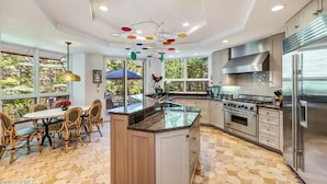 A modern kitchen with a central island, stainless steel appliances, and a dining area with wicker chairs. - Luxury Vail Mountain Estate – Ski Access • Spacious • Elegant Mountain Retreat (Vail)