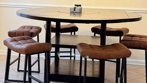 A round dining table with six stools, a chandelier with four lights, and a small object on the table. - Cozy 2-Bedroom Duplex in Little River (Little River)