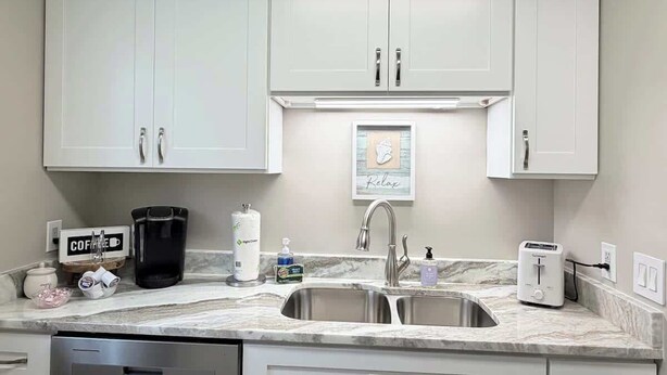 A kitchen with white cabinets, a double sink, a coffee maker, a toaster, and a sign that says "Relax". - Cozy 2-Bedroom Duplex in Little River (Little River)