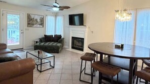 A living room with a fireplace, a television, a dining table, and a sofa. - Cozy 2-Bedroom Duplex in Little River (Little River)